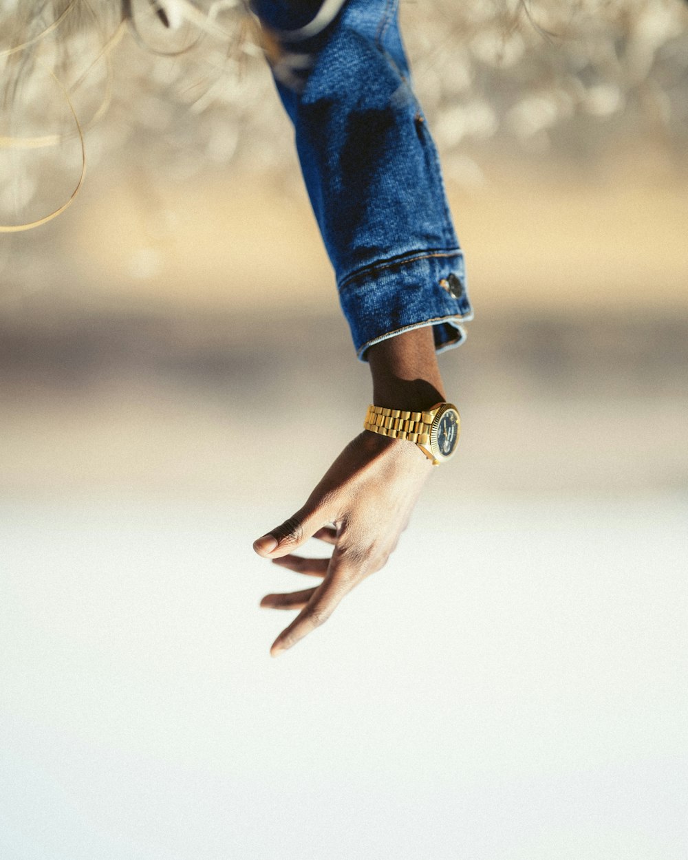 person in blue denim jeans wearing gold watch