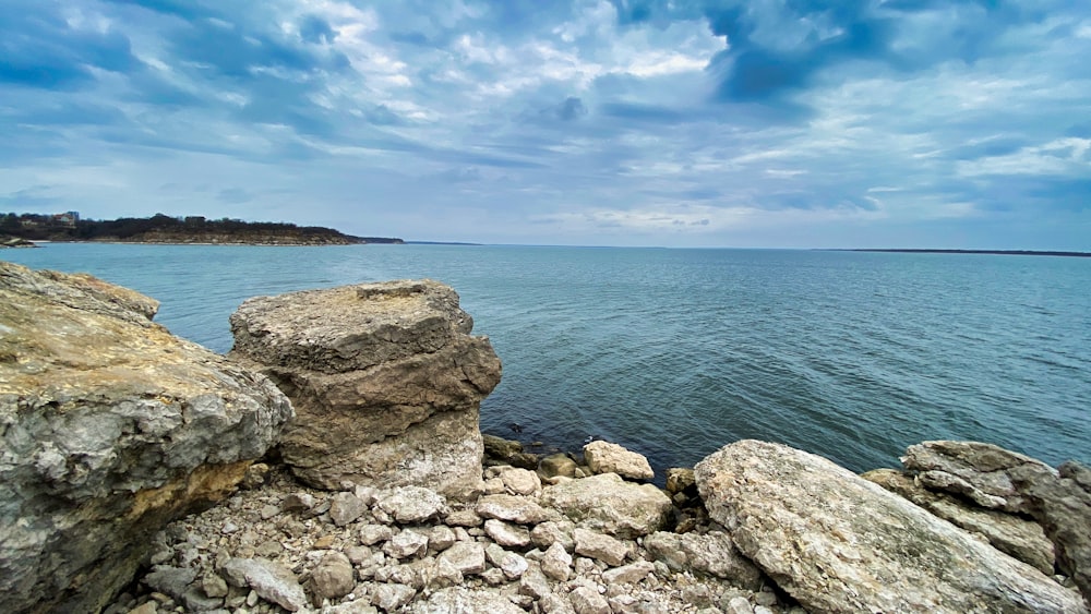 gray and brown rocks near body of water under blue sky during daytime