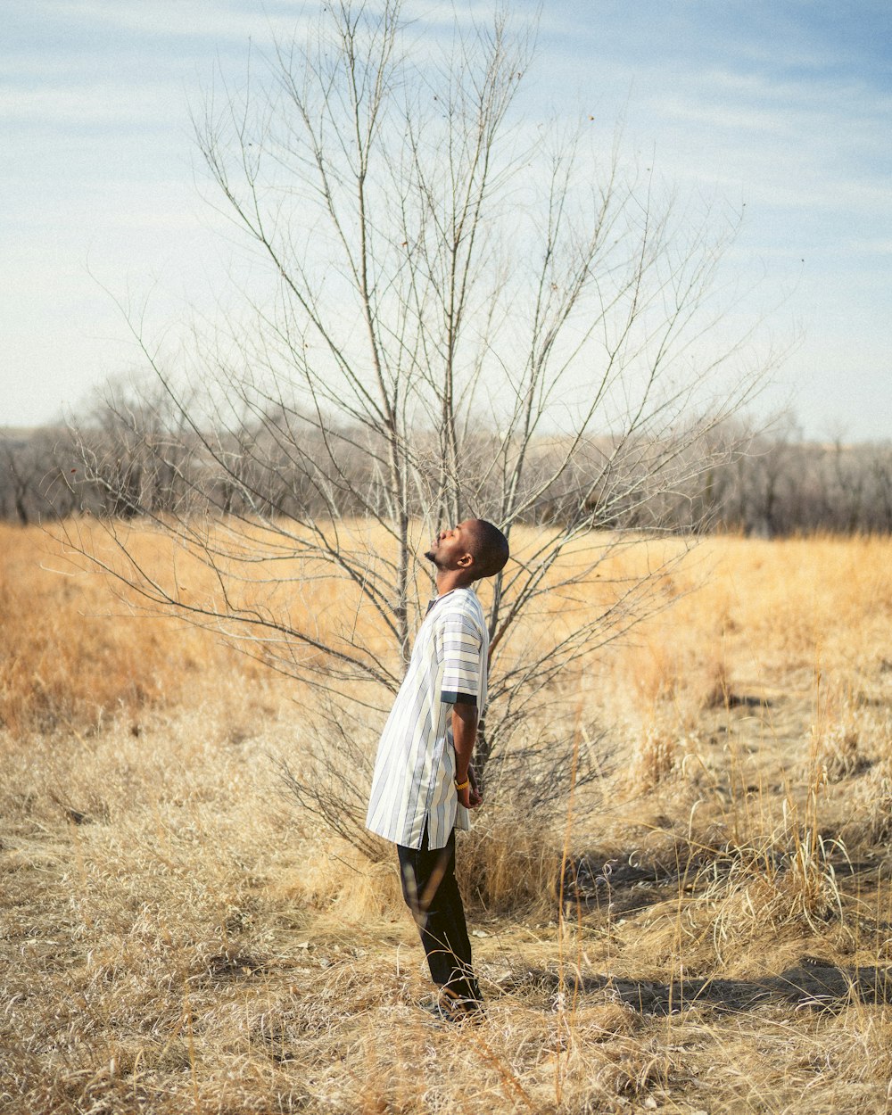 man in white dress shirt standing on brown grass field during daytime