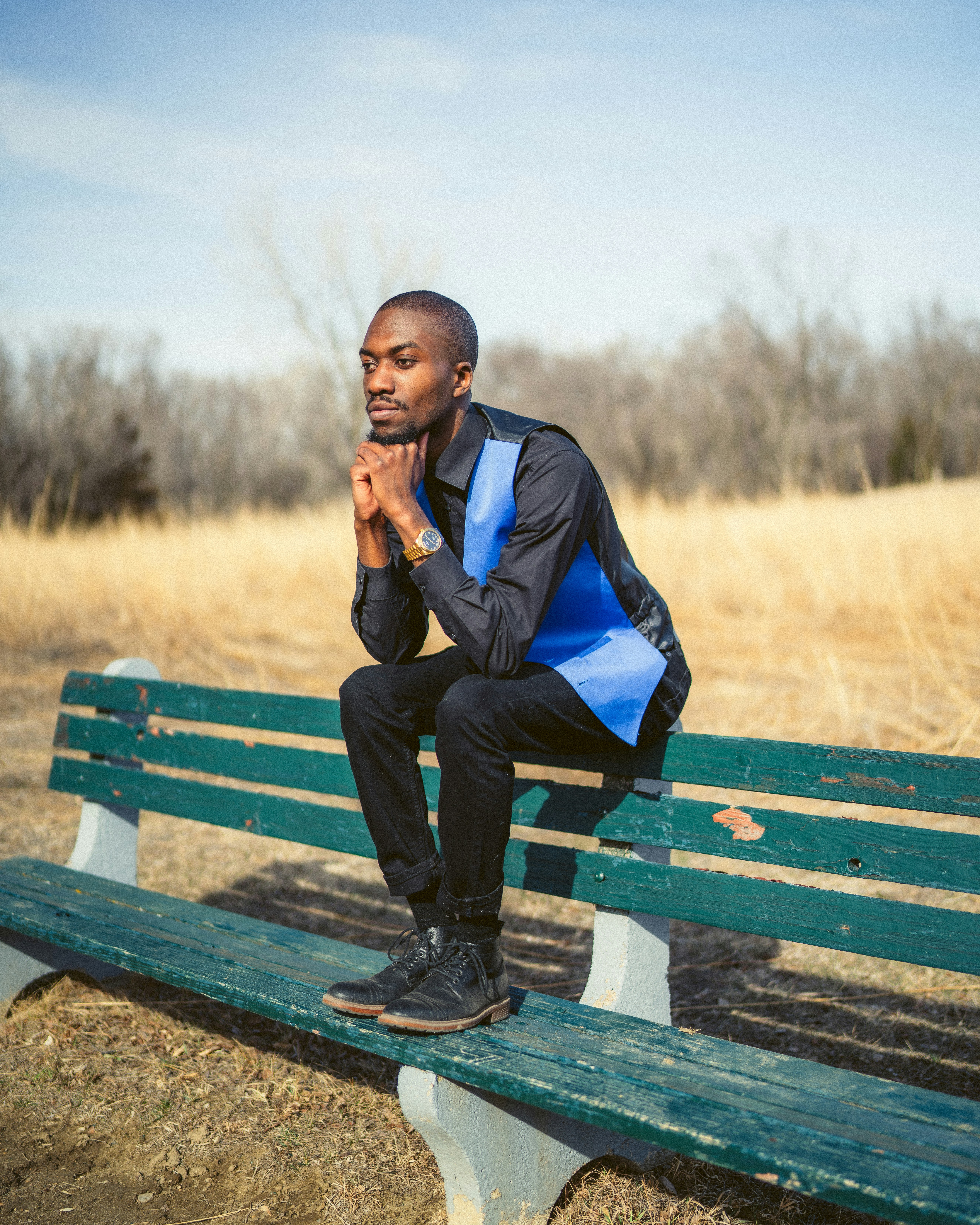 man in blue jacket sitting on brown wooden bench during daytime