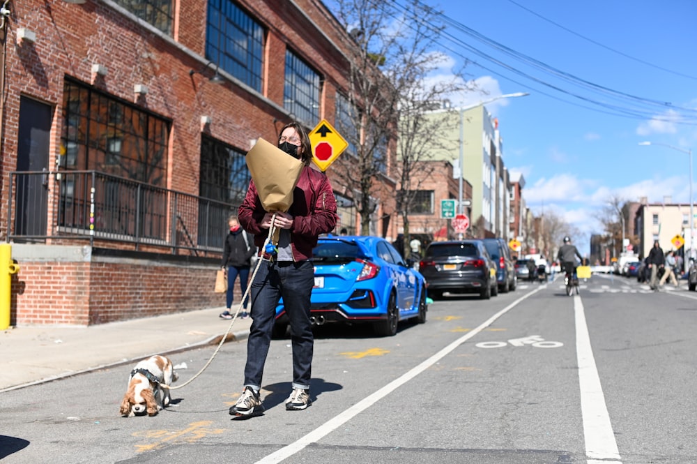 man in yellow jacket and black pants standing beside blue car during daytime