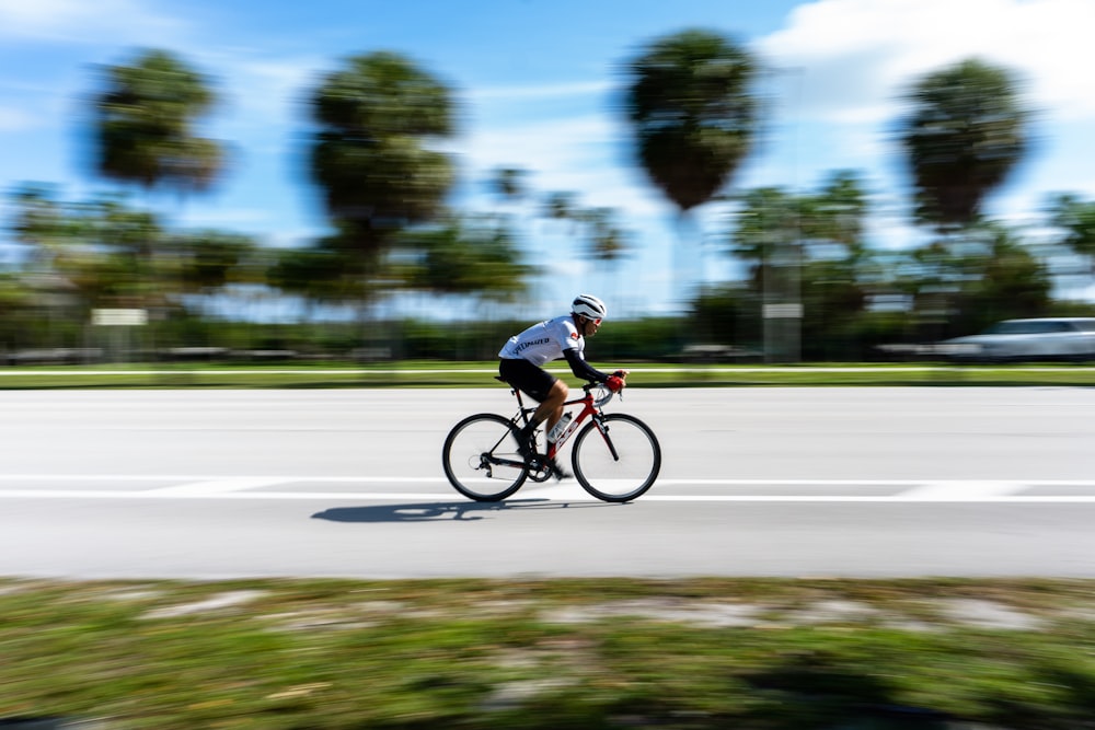 Hombre con camisa negra montando en bicicleta en la carretera durante el día
