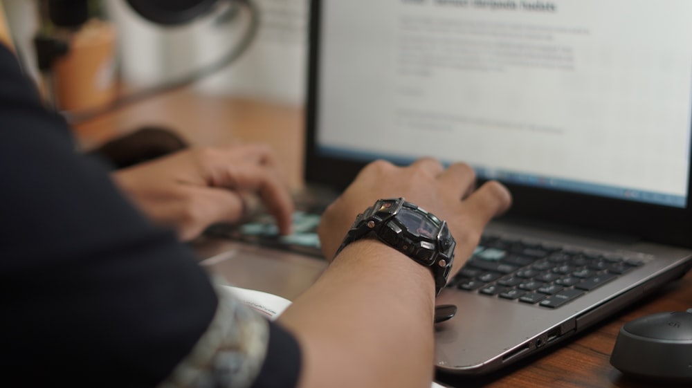 person wearing black and silver watch holding computer mouse