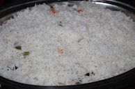 Steaming bowl of basmati rice with herbs.