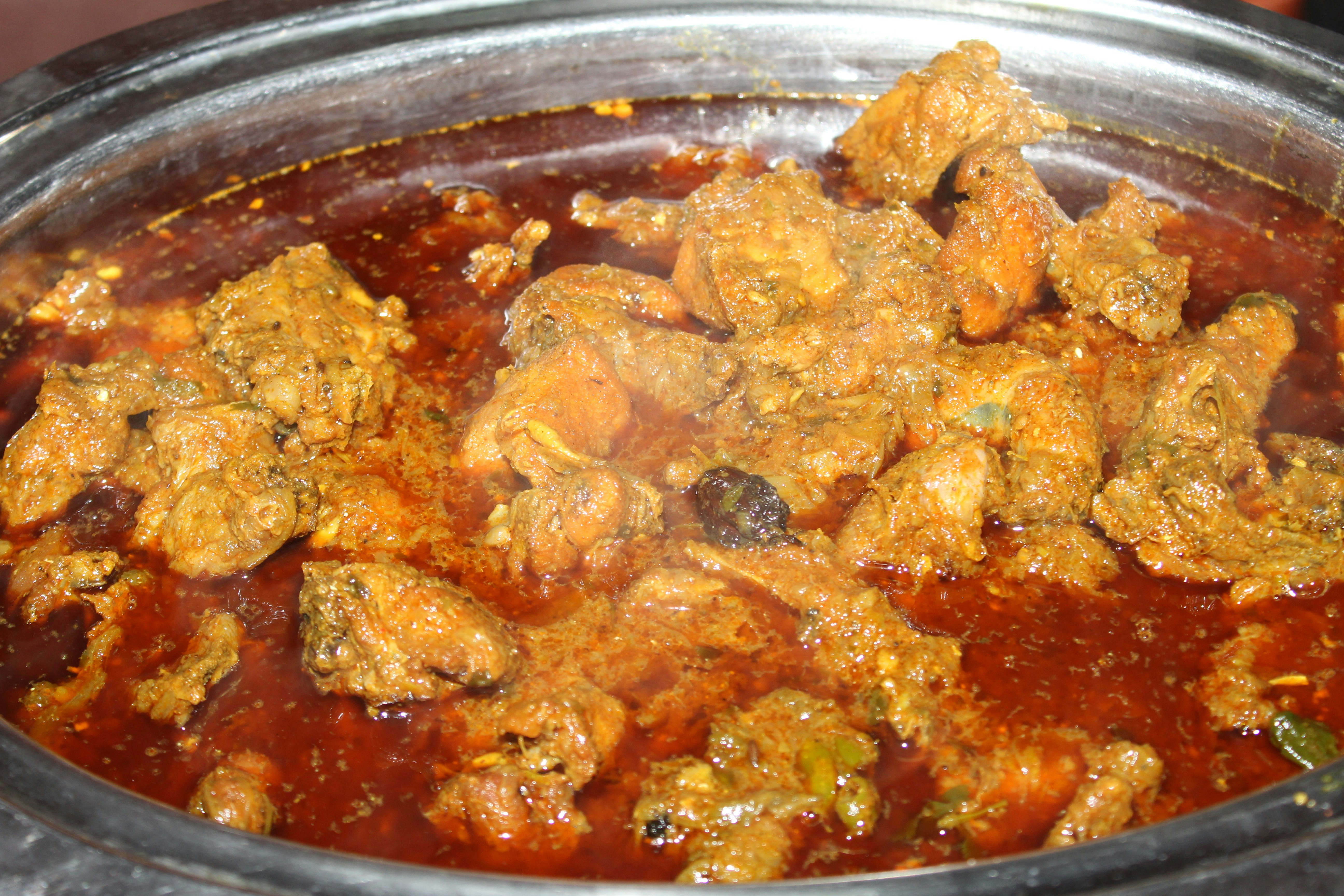 Spiced curry cut chicken pieces in a bowl with steam rising