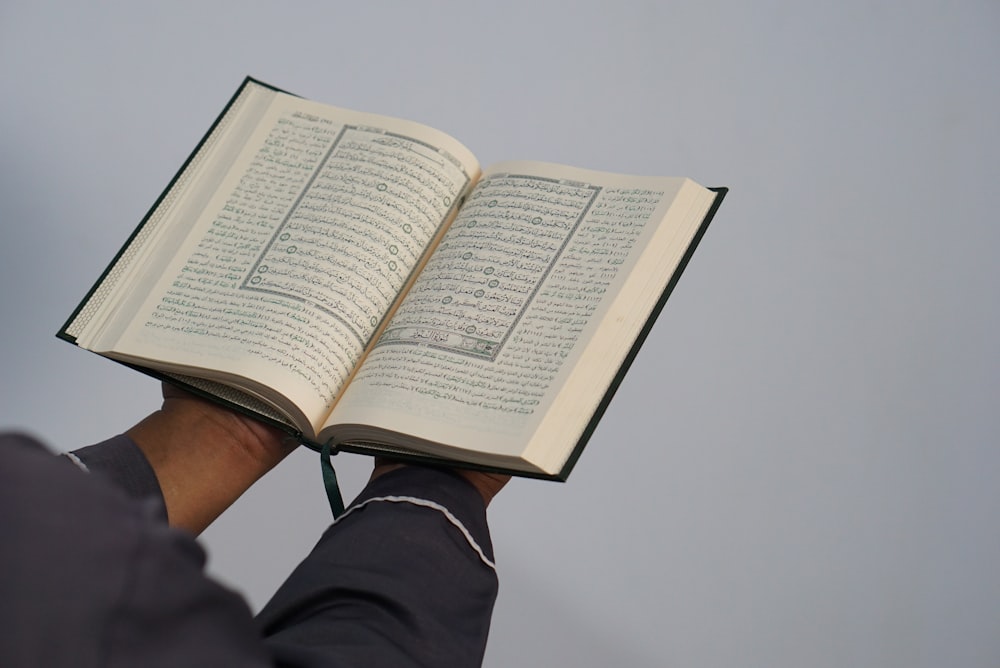 person reading book on white table