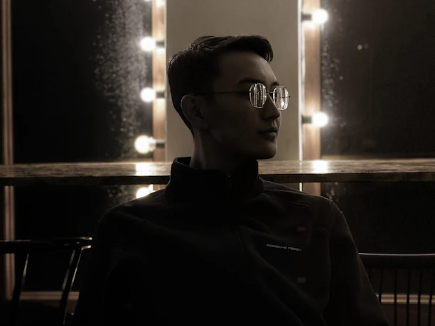 Portrait of Jason seated in a warmly lit room with deep jewel-toned decor and candles.