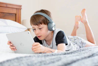 A cozy nighttime setting with a child listening to a calming bedtime meditation story on headphones.