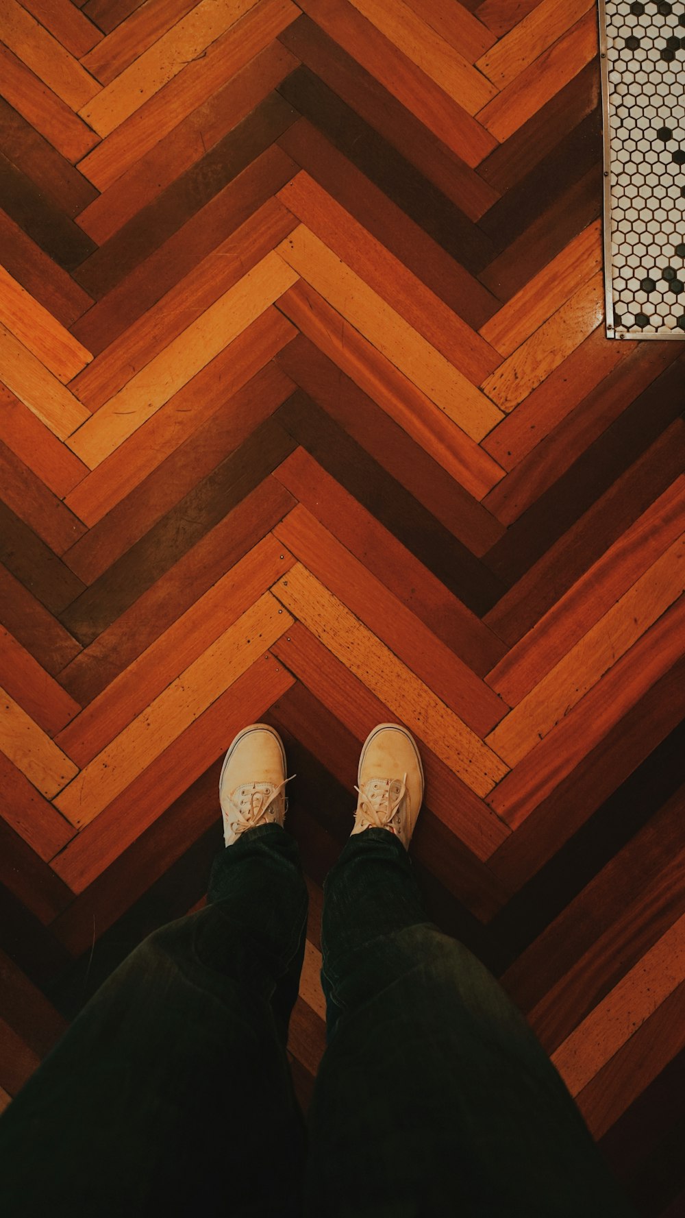 Persona che indossa scarpe da ginnastica bianche in piedi sul pavimento di legno marrone