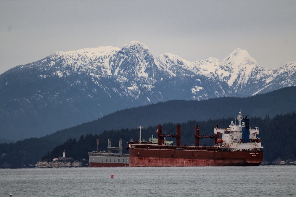 red and white ship on sea near snow covered mountain during daytime