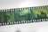 A strip of photographic film with multiple green-toned frames featuring various urban scenes, including a building with a dome and a street view. The film is labeled as AGFA EXCL CTx 100 and features both architectural elements and large numbers superimposed on the scenes.