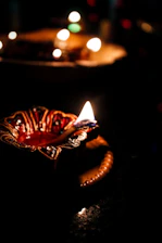 A serene image of a traditional Indian temple lamp glowing softly beside a bottle of Shree Aradhana Pooja Oil.