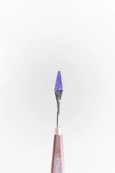 Close-up of a sleek, custom-designed surgical tool with a deep crimson handle, resting on a parchment background.