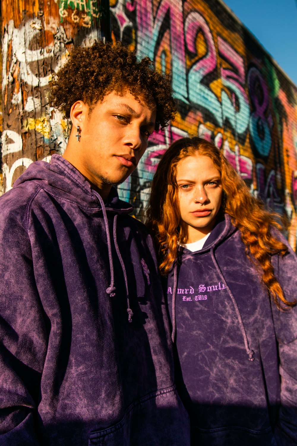 man in purple hoodie standing beside woman in black jacket