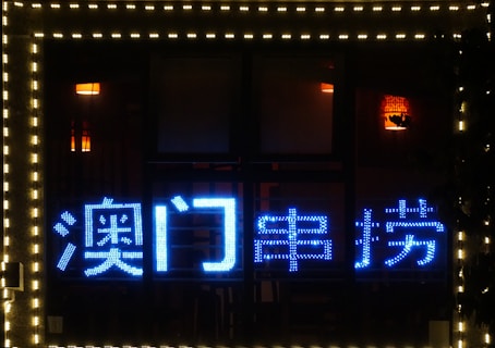 Bright blue neon Chinese characters are displayed on a dark background. The text is surrounded by warm lighting from two interior lamps, creating a contrast between the cool and warm tones. The perimeter of the image features small white lights.