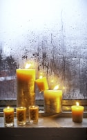 A collection of Sunshine Candles in various sizes and scents arranged on a cozy windowsill.
