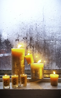 A collection of Sunshine Candles in various sizes and scents arranged on a cozy windowsill.