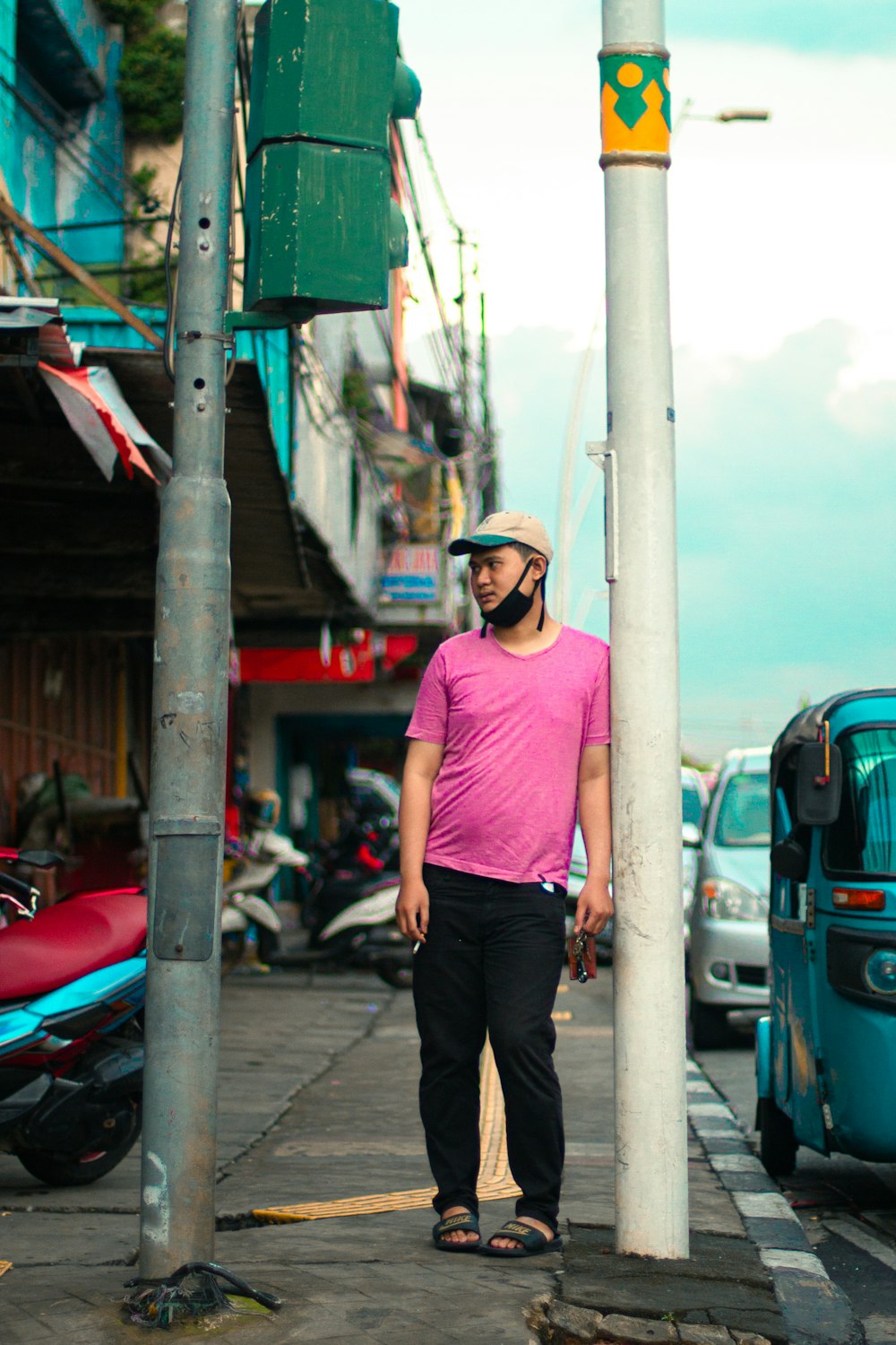 man in pink crew neck t-shirt and black pants standing on sidewalk during daytime