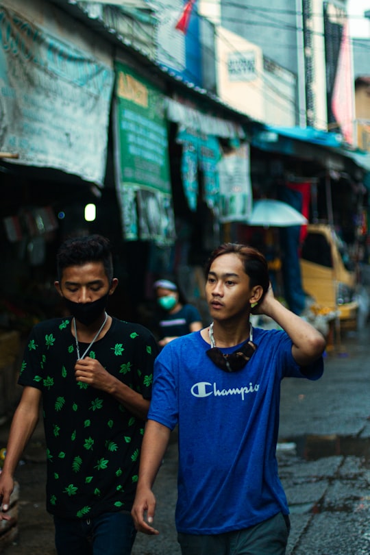 boy in blue crew neck t-shirt standing beside wall during daytime in Jatinegara Indonesia