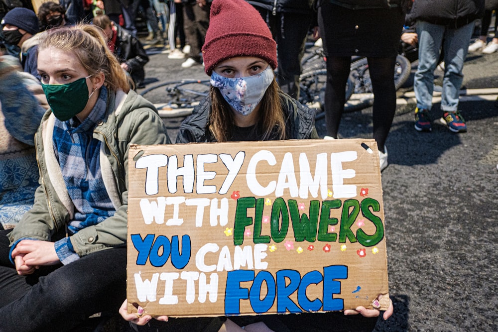 woman in red knit cap and gray jacket holding happy birthday signage