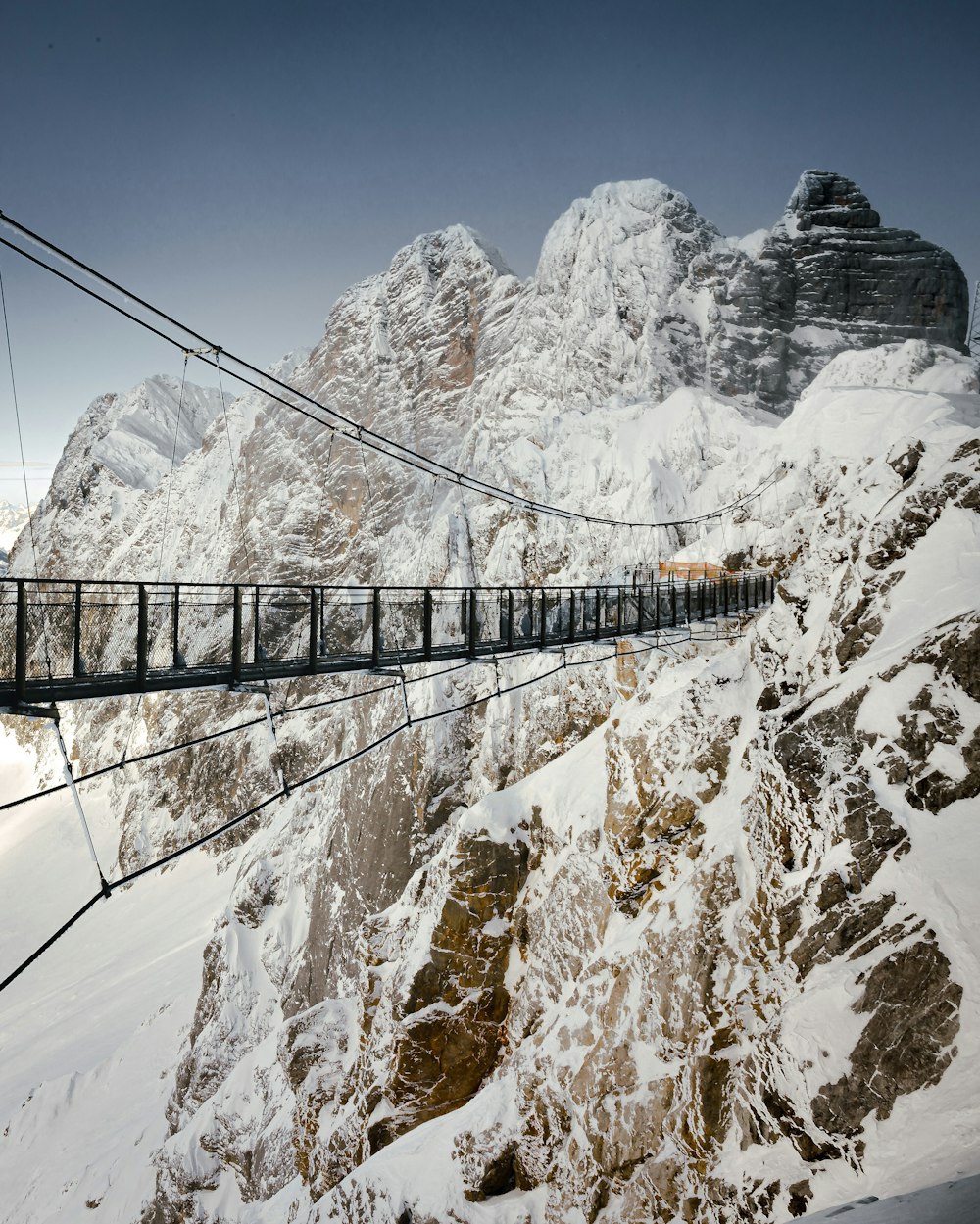 brown wooden bridge over snow covered mountain