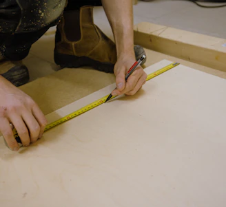 A skilled construction worker measuring wood on a building site.