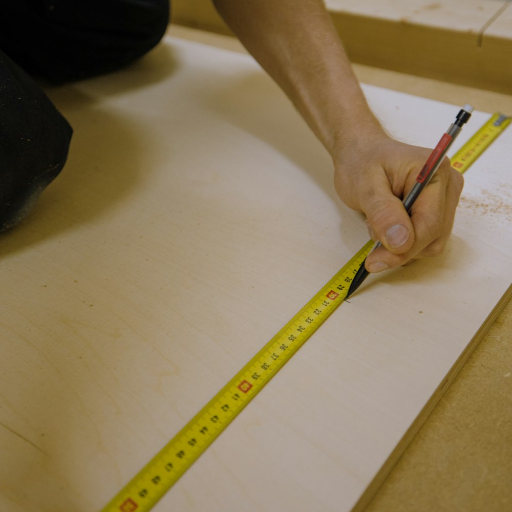 Person mit gelbem Bleistift auf weißem Tisch