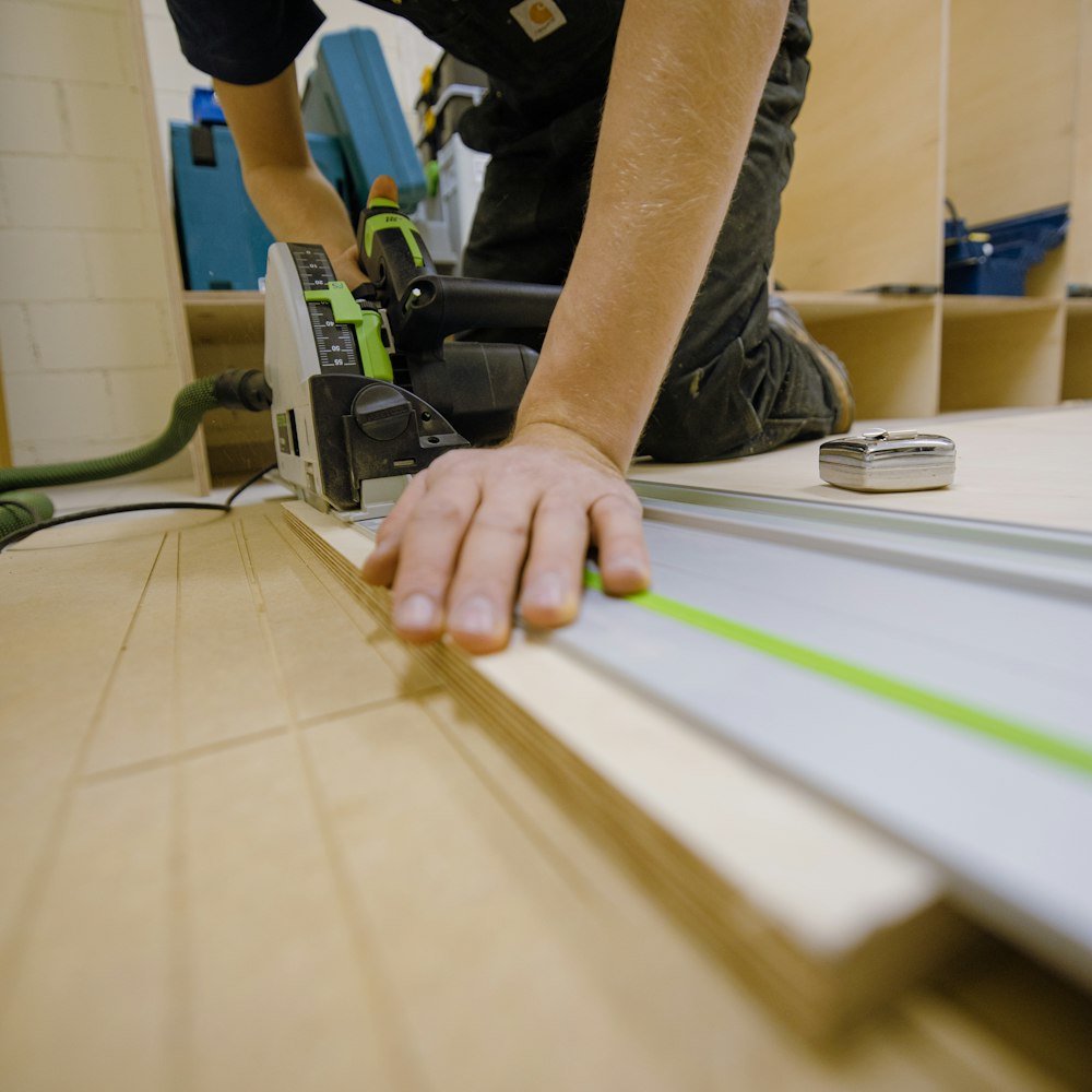 person in gray t-shirt holding green and white plastic tool