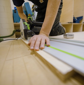 person in gray t-shirt holding green and white plastic tool