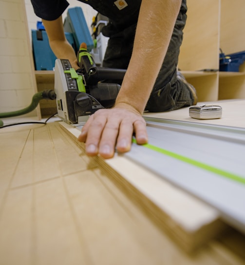 person in gray t-shirt holding green and white plastic tool