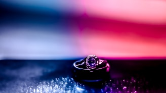 A close-up of a radiant blue sapphire set in an elegant gold ring, glowing softly against a dark royal blue background.