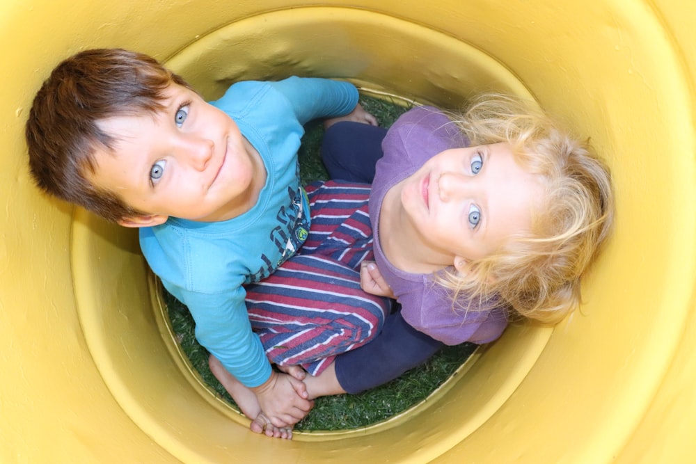 girl in blue and black stripe long sleeve shirt on yellow plastic container