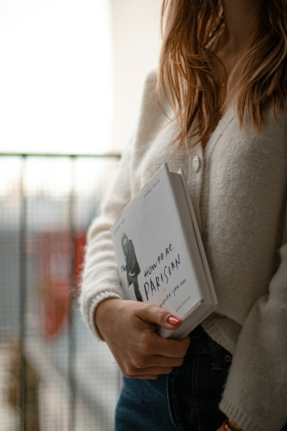 woman in gray sweater holding book