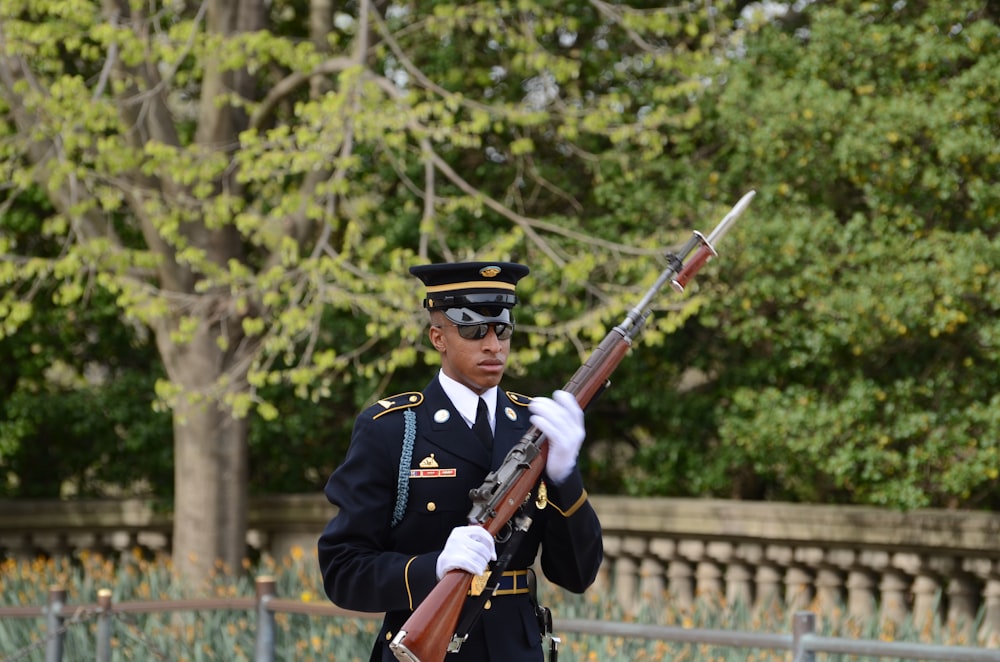 Hombre con uniforme de camuflaje negro y marrón sosteniendo un rifle