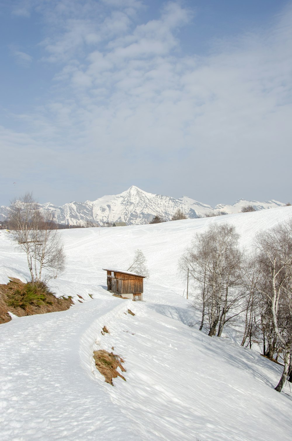 brown wooden house on snow covered ground near snow covered mountain during daytime