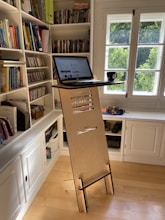 black laptop computer on white wooden book shelf