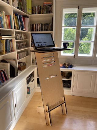 black laptop computer on white wooden book shelf