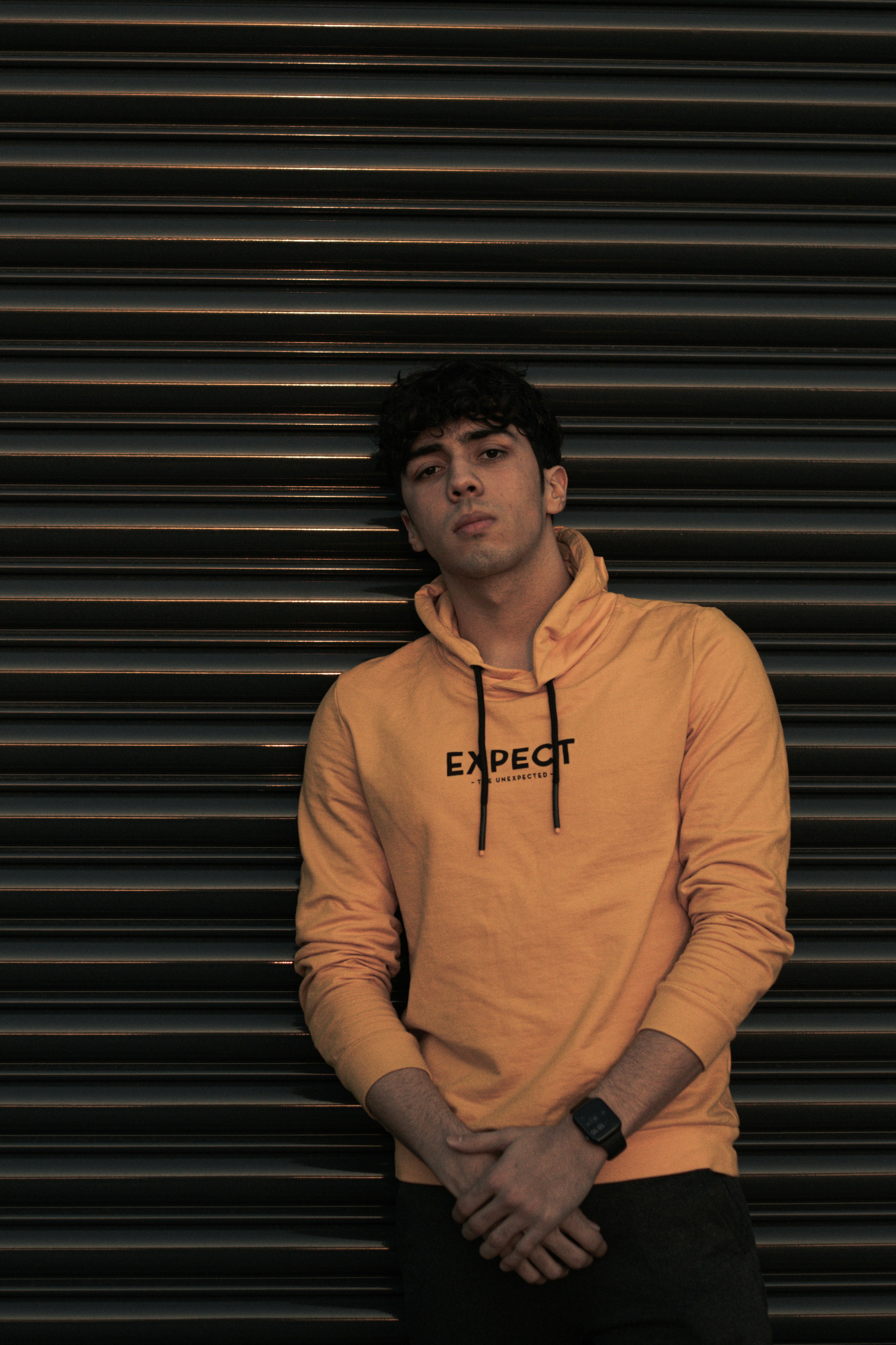 黒のロールアップ ドアの横に立っている茶色のプルオーバー パーカーの男の写真 Unsplashで見つける50mmの無料写真