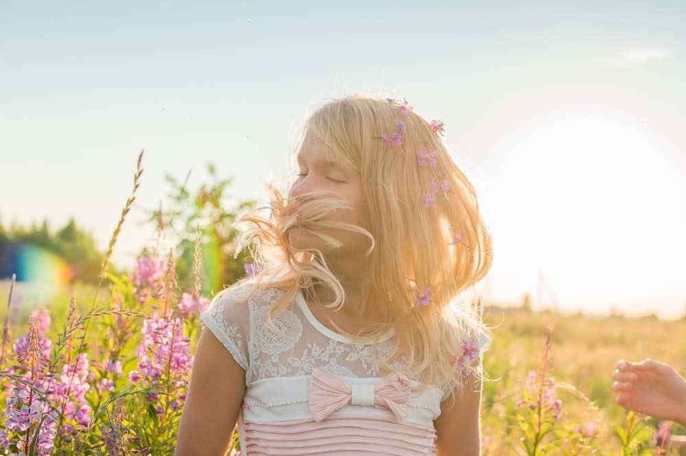 girl in white cap sleeve shirt standing on yellow flower field during daytime