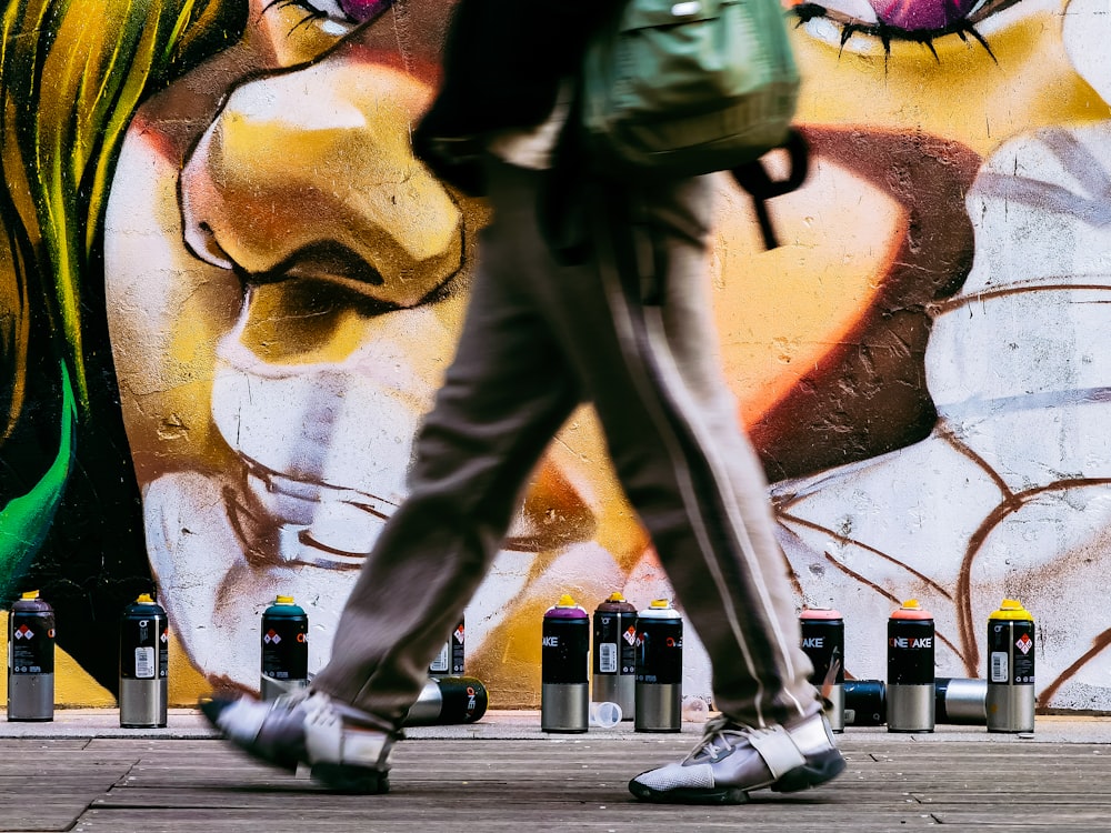Una persona caminando más allá de una pared con graffiti en ella
