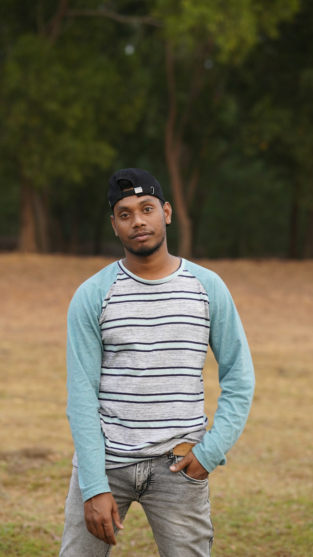 man in gray and white striped long sleeve shirt and black fitted cap standing on brown