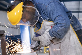 person in blue denim jeans and white and gray gloves holding yellow plastic bucket
