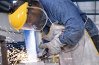 person in blue denim jeans and white and gray gloves holding yellow plastic bucket