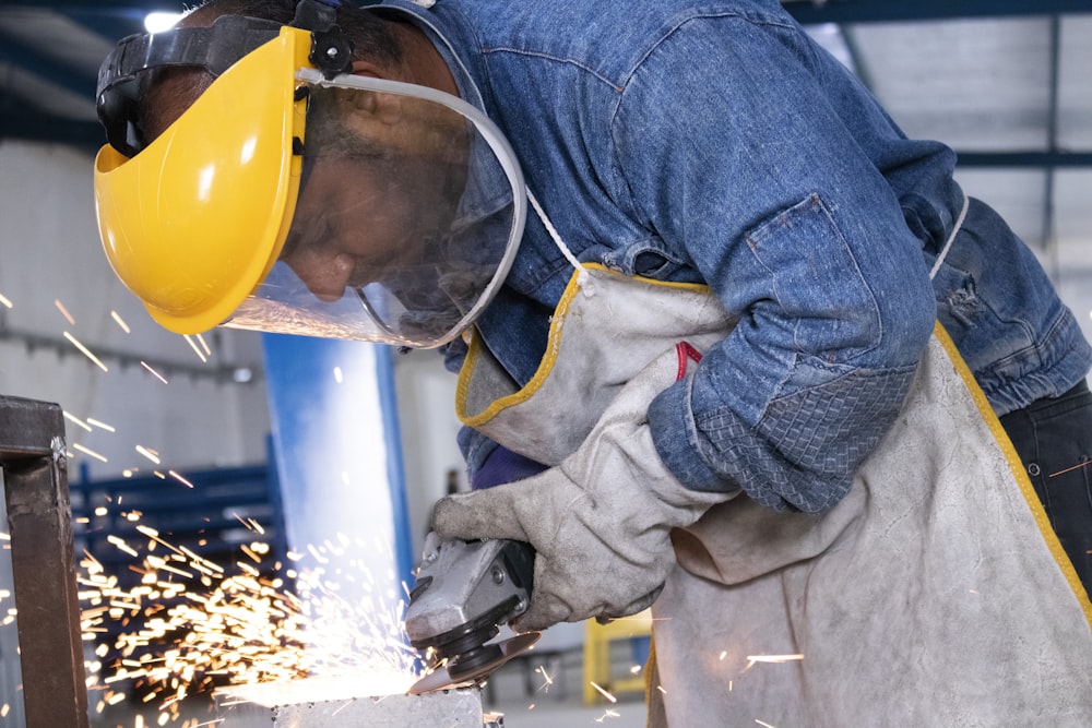 person in blue denim jeans and white and gray gloves holding yellow plastic bucket