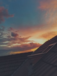 A clean tile roof with a warm orange glow of the setting sun in the background.