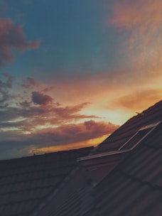A clean tile roof with a warm orange glow of the setting sun in the background.