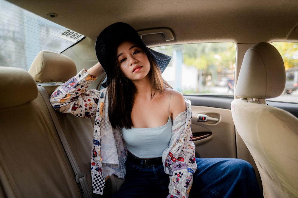 woman in white tank top and blue pants sitting on car seat