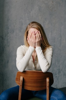 woman in white long sleeve shirt covering her face