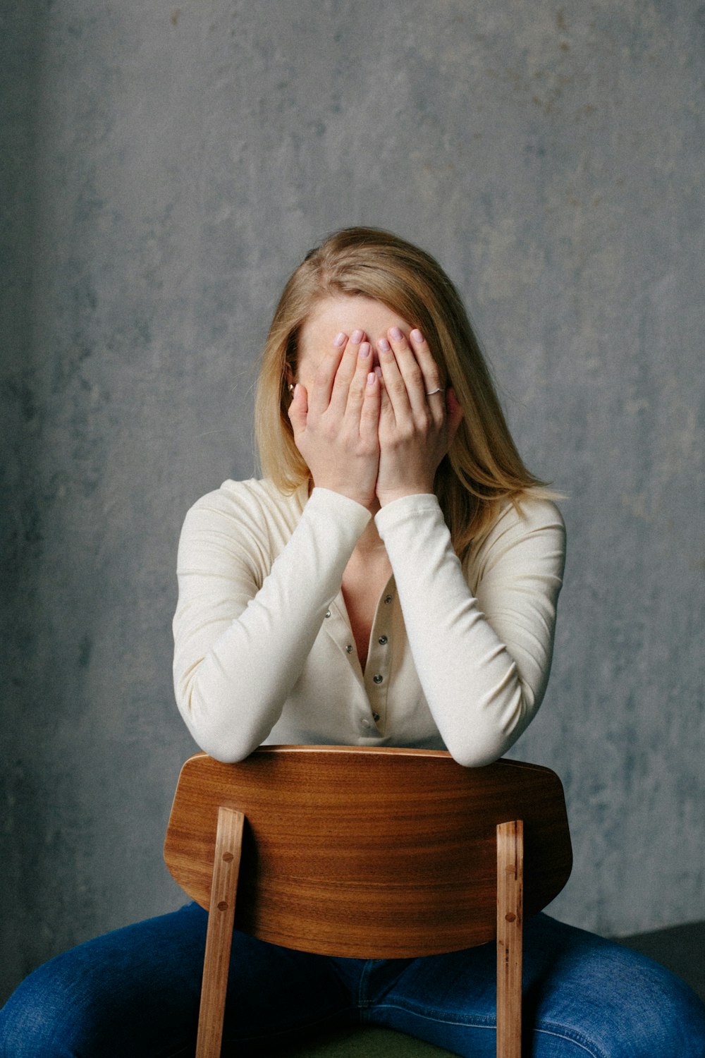 woman in white long sleeve shirt covering her face