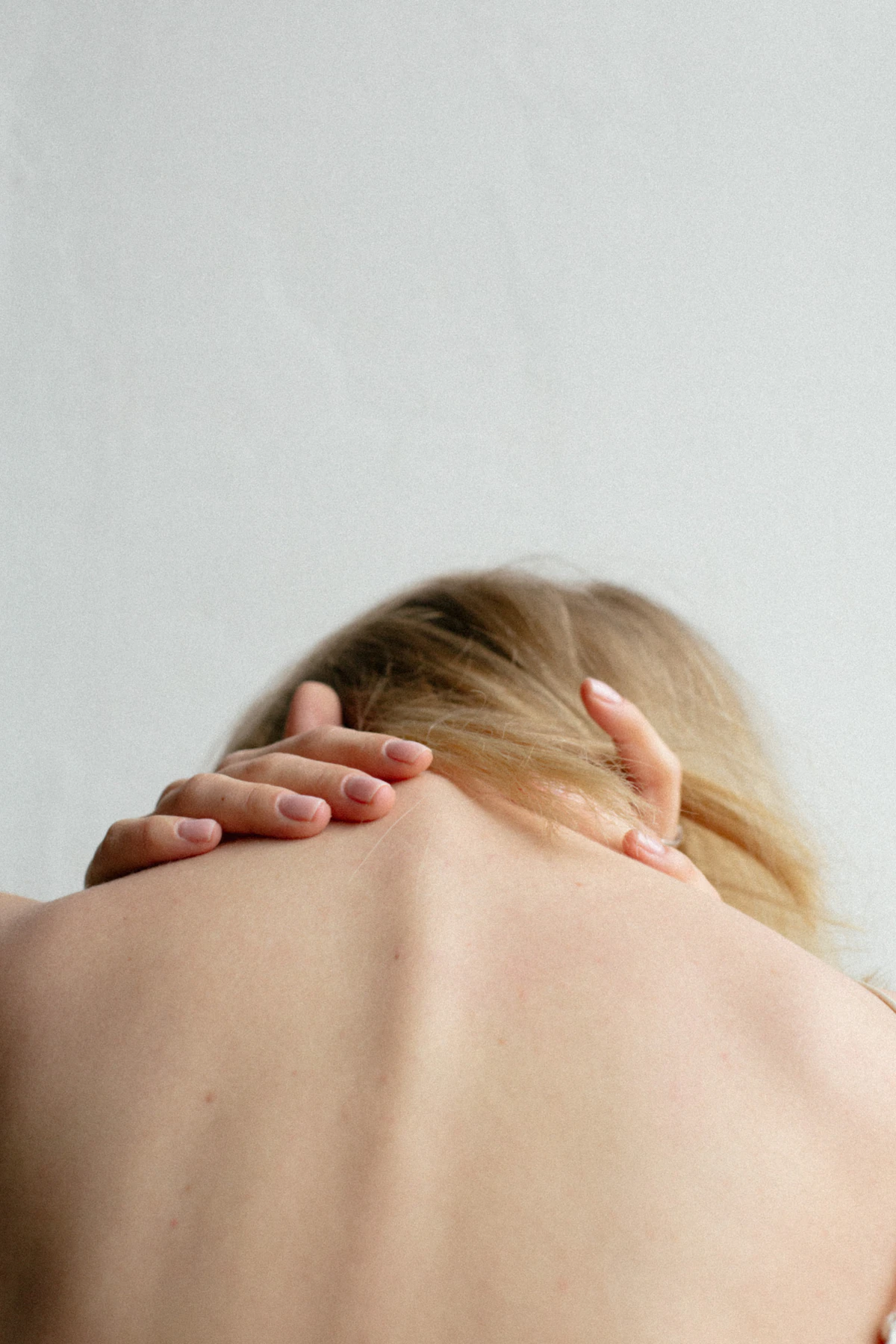 Person holding the back of their neck with both hands, a common sign of neck discomfort